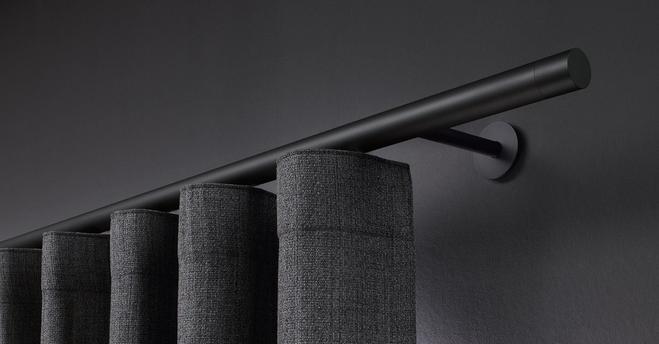 Dunkler Vorhang an schwarzer Gardinenstange vor dunkler Wand