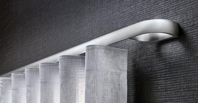 Moderne silberne Gardinenstange mit hellgrauen Vorhängen vor dunkler Wand